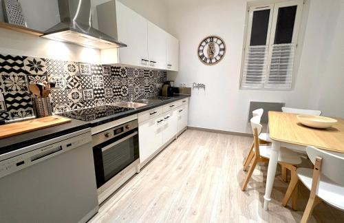 une cuisine avec des placards blancs, une table et une salle à manger dans l'établissement T2 Hyper centre 3 étoiles Rue des Bains, à Aix-les-Bains