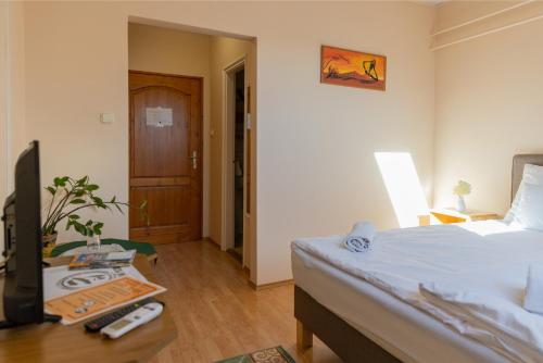 a bedroom with a bed and a table with a tv at Betli Panzió in Zalaegerszeg