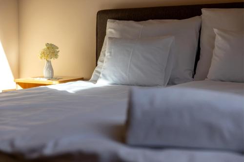a bed with white sheets and a vase of flowers on a table at Betli Panzió in Zalaegerszeg