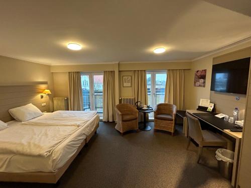 a hotel room with a bed and a desk at Hotel Atlas in Zeebrugge