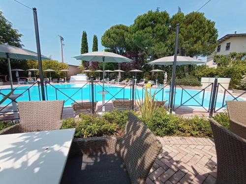a pool with tables and chairs and umbrellas at Park Residence Il Gabbiano in Moniga