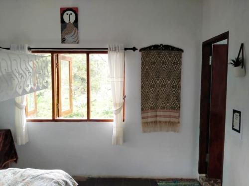 a bedroom with white walls and a window with curtains at Sumatra Orangutan Discovery Villa in Bukit Lawang