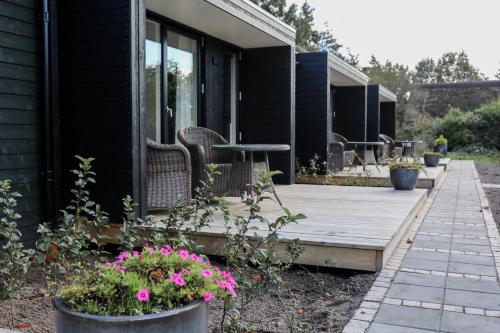 a wooden porch with chairs and flowers on a house at BLÅBJERGGAARD - Hennebysvej 60 in Henne Strand