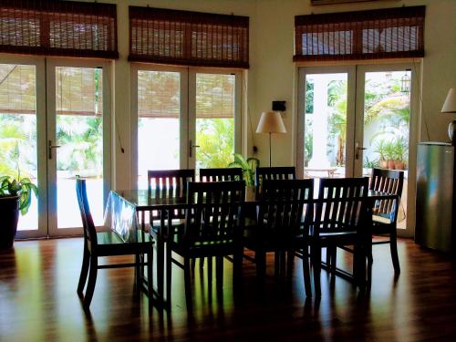 a dining room with a table and chairs and windows at Rumah Putih B&B near KLIA in Sepang