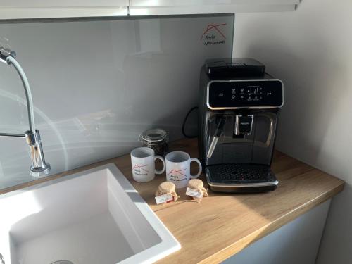 eine Küchentheke mit Kaffeemaschine und Kaffeetassen in der Unterkunft Apartamenty Amira w kompleksie Apartamenty Piano in Świeradów-Zdrój