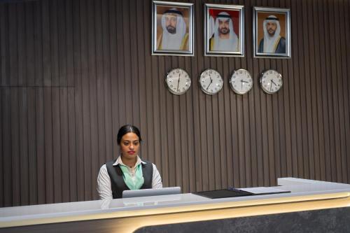 a woman sitting at a desk with a laptop at Hotel Holiday International in Sharjah