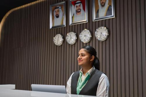 a woman sitting at a desk with a laptop at Hotel Holiday International in Sharjah