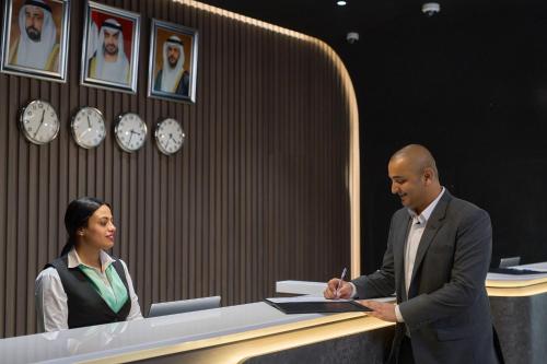 a man and a woman standing behind a desk at Hotel Holiday International in Sharjah