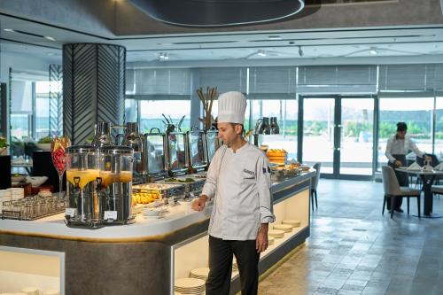 a chef standing in front of a counter in a kitchen at Hotel Holiday International in Sharjah