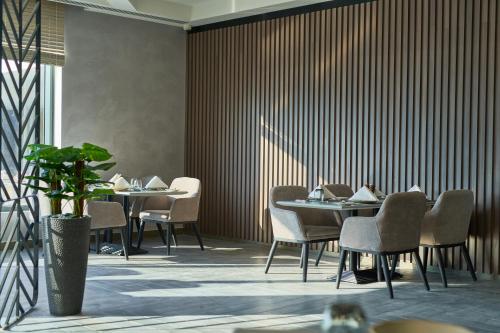 a dining room with tables and chairs and a plant at Hotel Holiday International in Sharjah