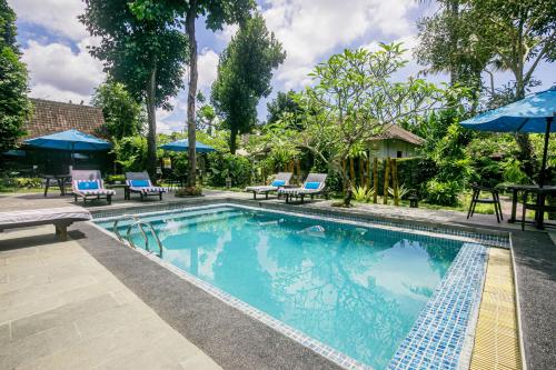 a swimming pool with chairs and umbrellas in a resort at Canvas Escape Resort in Ubud