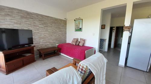 ein Wohnzimmer mit einem Sofa und einem Flachbild-TV in der Unterkunft DEPARTAMENTO en POTRERO DE LOS FUNES frente al lago in Potrero de los Funes