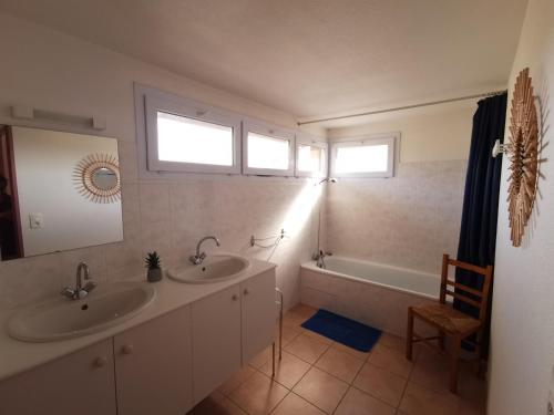 baño con 2 lavabos, bañera y 2 ventanas en Rouvenac 