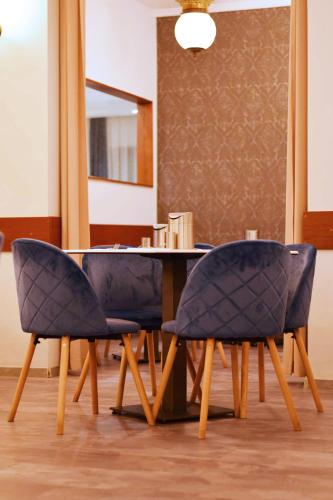 a dining room table with two blue chairs in front of it at Hotel Palatinus in Sopron