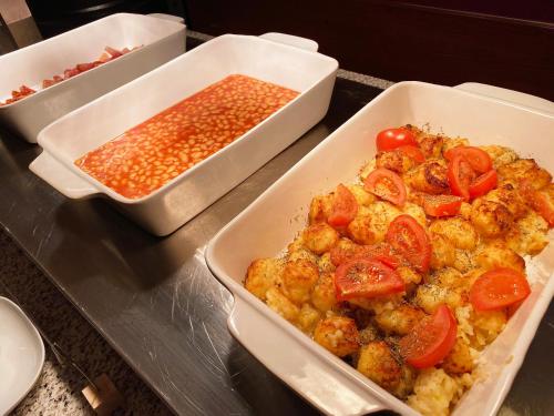 two trays of food with tomatoes and beans on a counter at Hotel Palatinus in Sopron
