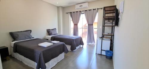 two beds in a room with a window and a ladder at Euro Flat Hotel in Parnaíba