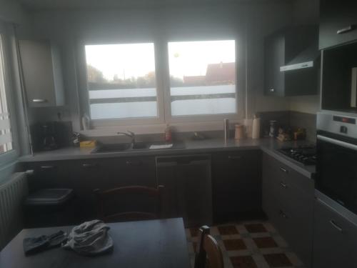 a kitchen with a sink and two windows in it at Gîte chez Danielle in Blessy