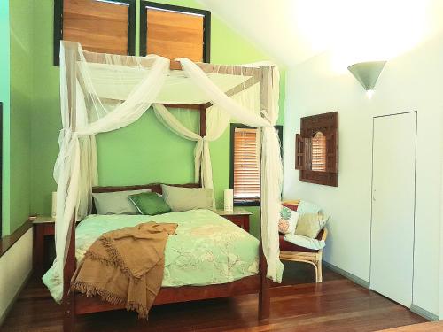 a bedroom with a canopy bed and a chair at Sky Island Studios in Mount Tamborine