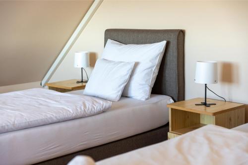 a bedroom with two beds with white pillows and lamps at Betli Panzió in Zalaegerszeg