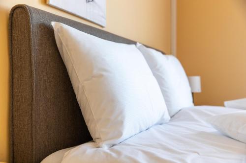 a bed with a white pillow on top of it at Betli Panzió in Zalaegerszeg
