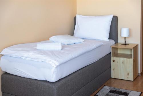 a bed with two white pillows and a night stand at Betli Panzió in Zalaegerszeg
