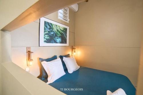 1 dormitorio con 1 cama azul y 2 almohadas en Le Ti Bourgeois, en Rivière-Salée