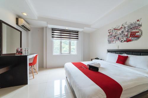 a bedroom with a bed and a desk and a window at RedDoorz Plus at One Liberty Hotel Kalayaan Avenue in Manila