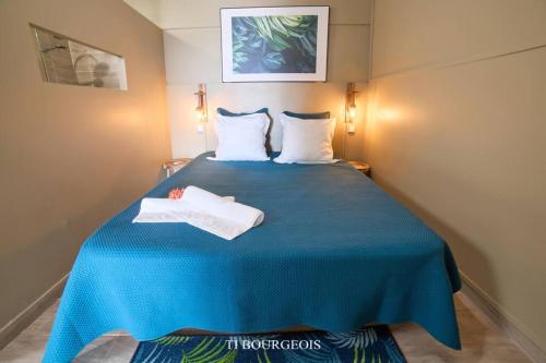 a blue bed with two white towels on it at Le Ti Bourgeois in Rivière-Salée