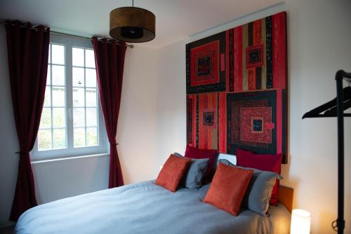 a bedroom with a blue bed with red pillows at Les Gites By Carpe Diem in Les Andelys