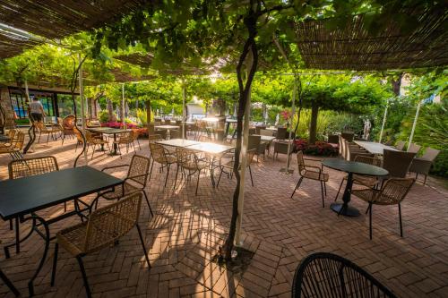 a patio with tables and chairs under a tree at Park Residence Il Gabbiano in Moniga