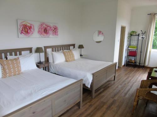 two beds in a bedroom with white walls and wood floors at Rumah Putih B&B near KLIA in Sepang