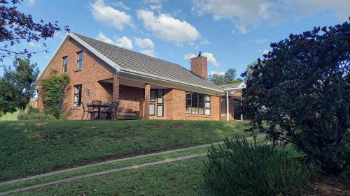 a brick house with a chimney on a lawn at Misty peaks Cloudlands in Bergview