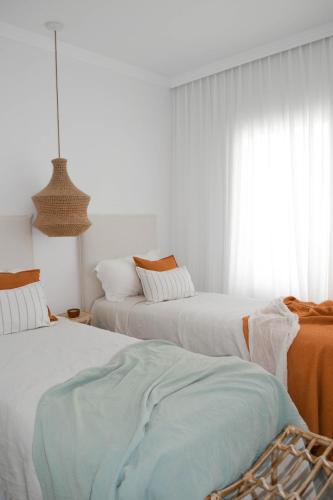 een witte kamer met 2 bedden en een raam bij Casa Alsina in Chascomús