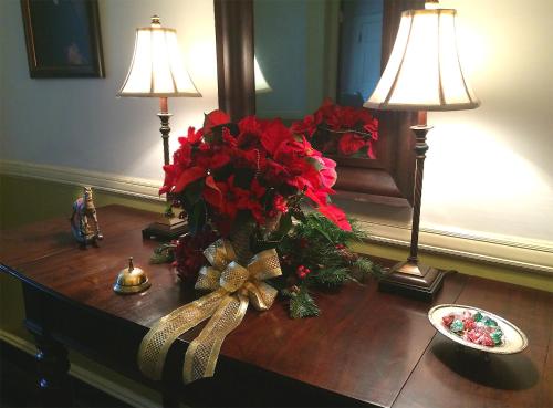a table with a vase of red flowers and two lamps at Rachael's Dowry Bed and Breakfast in Baltimore