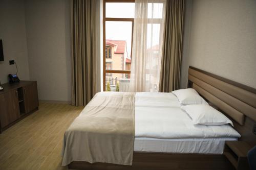 1 dormitorio con cama blanca y ventana en Marrone Hotel Tsaghkadzor, en Tsaghkadzor