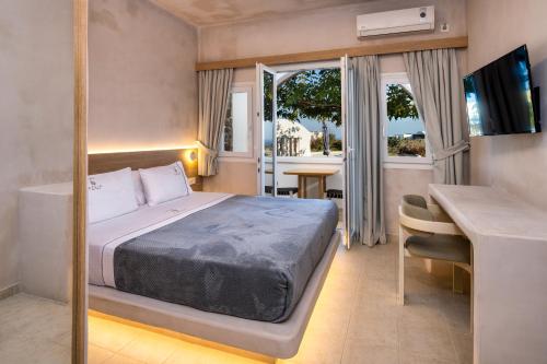 a bedroom with a bed and a desk and a window at Aelia Luxury Suites in Karterados