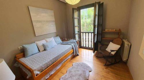 um quarto com uma cama, uma cadeira e uma janela em Casa Vacacional Guelu em Parres de Llanes