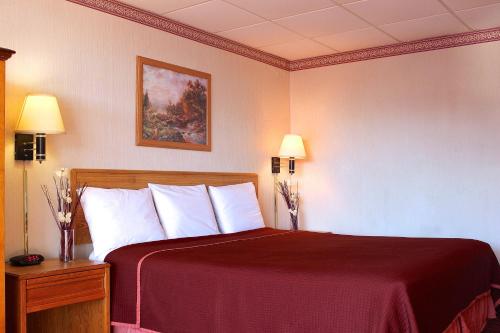 a bedroom with a bed with a red blanket and two lamps at Regency Inn Richmond in Richmond