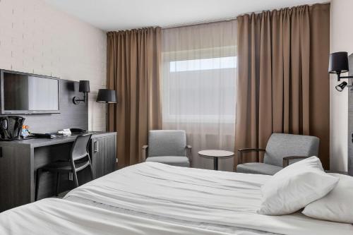 a hotel room with a bed and a desk and chairs at Best Western Hotel Scheele in Köping