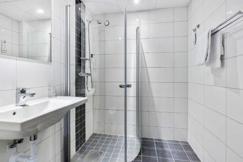 baño blanco con ducha y lavamanos en Best Western Hotel Scheele, en Köping