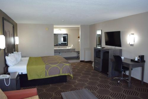 a hotel room with a bed and a desk and a television at Super 8 by Wyndham Huntersville/Charlotte Area in Huntersville