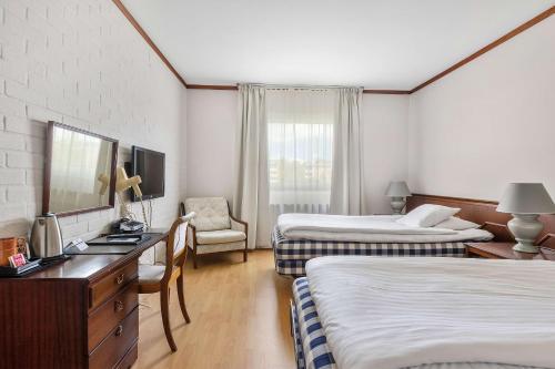a hotel room with two beds and a desk at Best Western Hotel Scheele in Köping