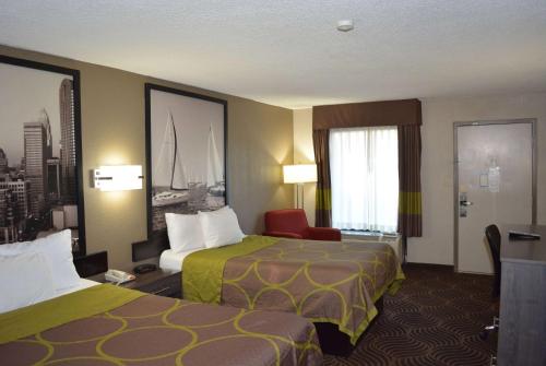 a hotel room with two beds and a chair at Super 8 by Wyndham Huntersville/Charlotte Area in Huntersville