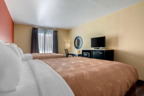 a hotel room with a bed and a flat screen tv at Quality Inn Phenix City Columbus in Phenix City