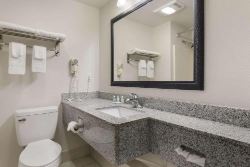a bathroom with a sink and a toilet and a mirror at Quality Suites I-44 in Tulsa