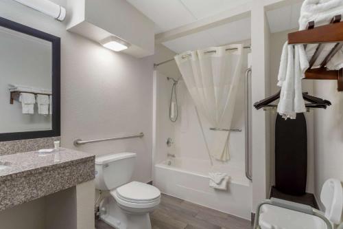 a bathroom with a toilet and a tub and a sink at Clarion Pointe Kimball By Choice Hotels in Kimball
