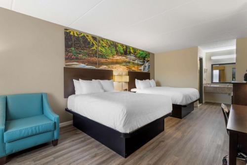 Cette chambre d'hôtel comprend deux lits et une chaise bleue. dans l'établissement Clarion Pointe Kimball, TN, à Kimball