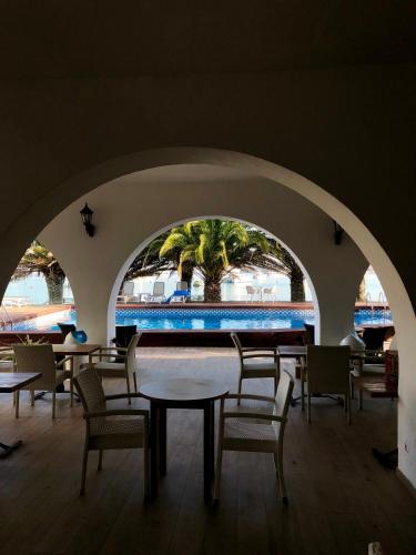 a room with tables and chairs and a palm tree at Hotel Tagomago in San Antonio Bay