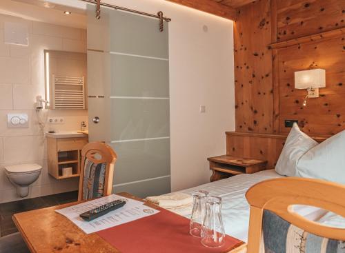 a bedroom with a bed with a table and a bathroom at Hotel Mitterhof in Gerlos