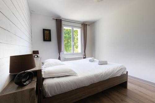 a bedroom with a bed with a lamp and a window at Maison des Grands Champs in Saint-Aignan